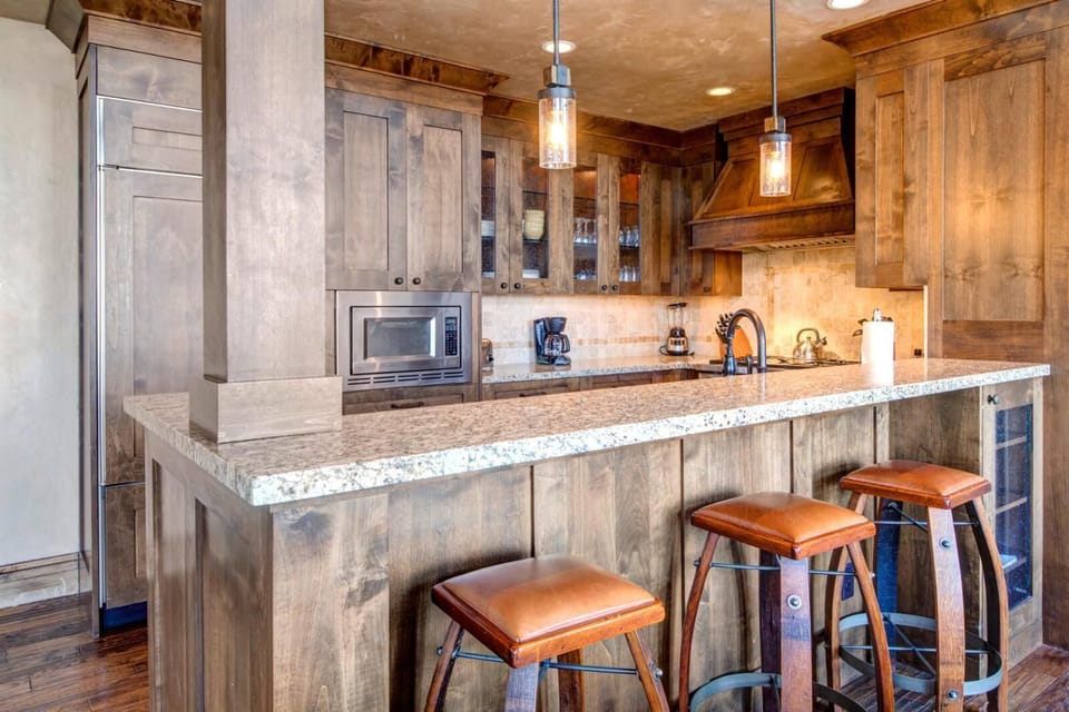 Warm wood cabinetry, pendant lighting, and stainless steel finishes bring style and function to the kitchen.