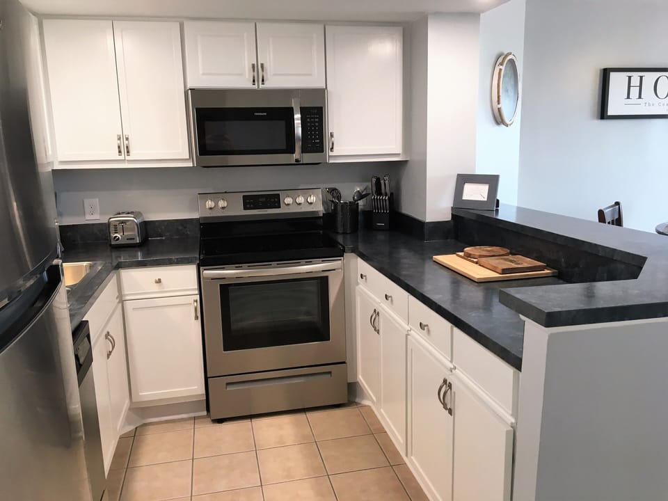 Kitchen that is fully stocked for cooking. Pots and pans, silverware, plates.
