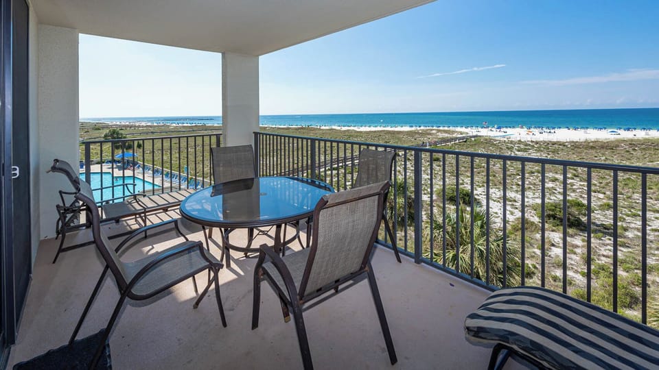 Balcony seating offers a tranquil spot to enjoy views of the pool and the beach with white sand and turquoise gulf