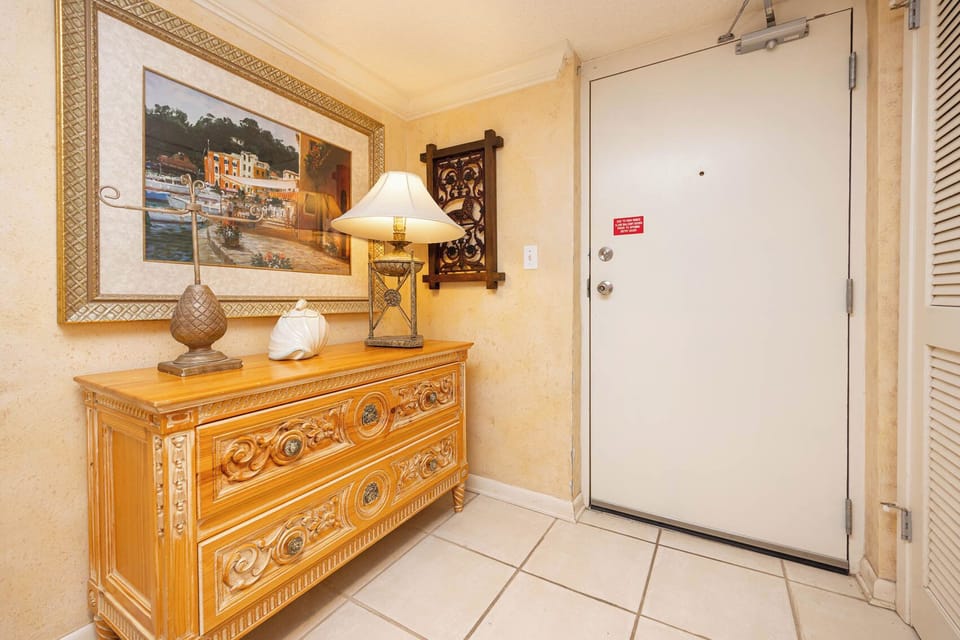 Welcoming entryway features a decorative wooden chest, elegant lamp, and vibrant artwork, creating a warm atmosphere