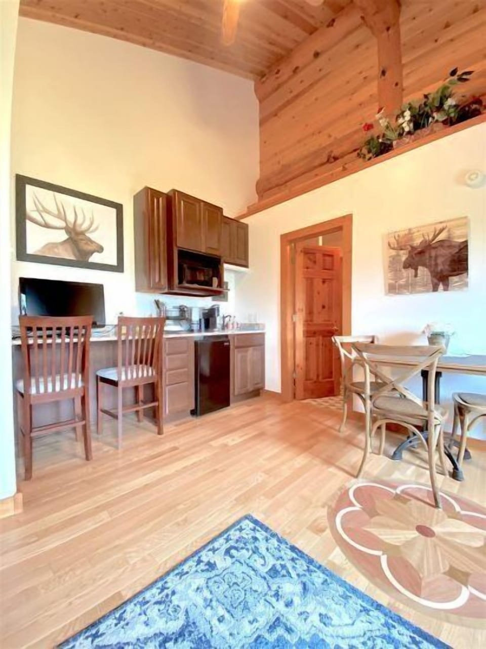 Main room with open living area, dining nook and kitchenette with bar style seating and smart tv.