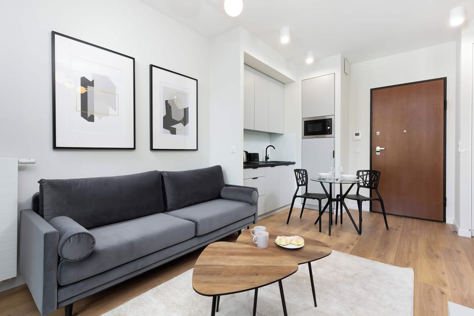 A stylish sofa with a coffee table, wall art, and minimalist furnishings in a bright setting.