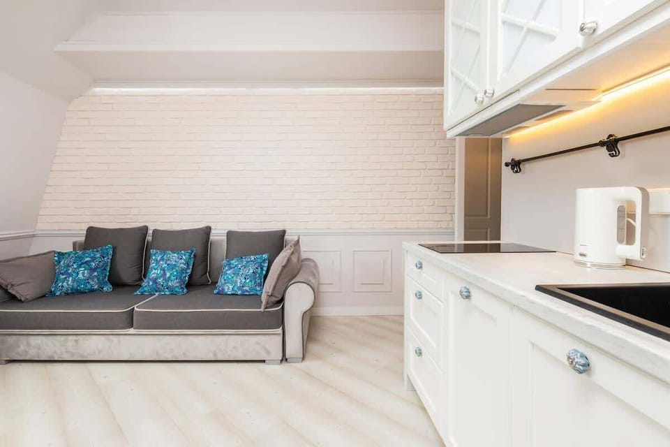 A detailed view of the living room’s gray sofa, accented with turquoise throw pillows, alongside an adjacent kitchen counter.