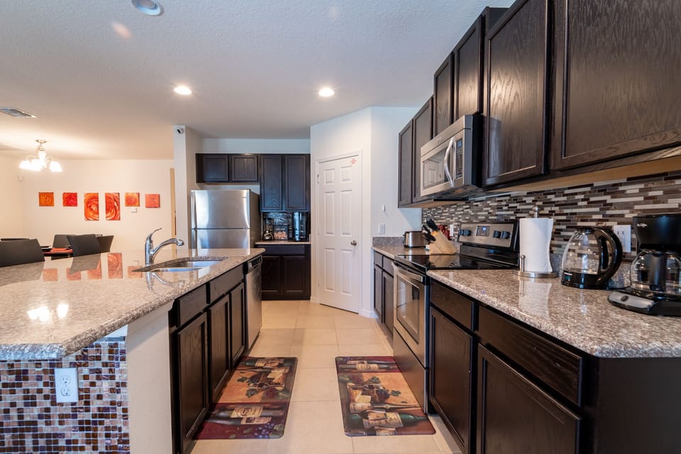 Sleek galley style kitchen with stone counter tops and stainless appliances