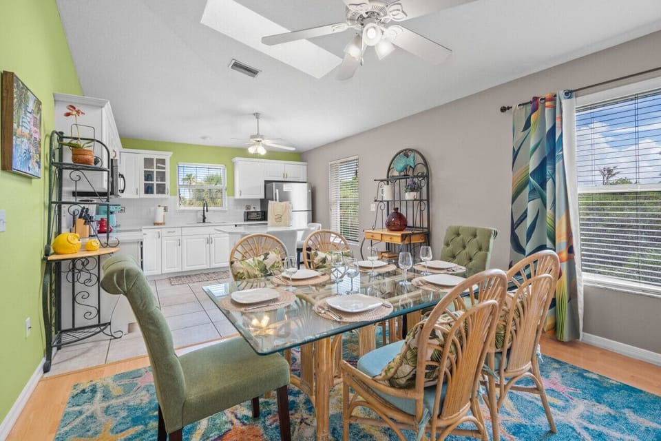 Sarasota, Florida retreat featuring colorful dining with a glass-top table, tropical rug, and bright kitchen—perfect for joyful meals and sun-filled coastal living.