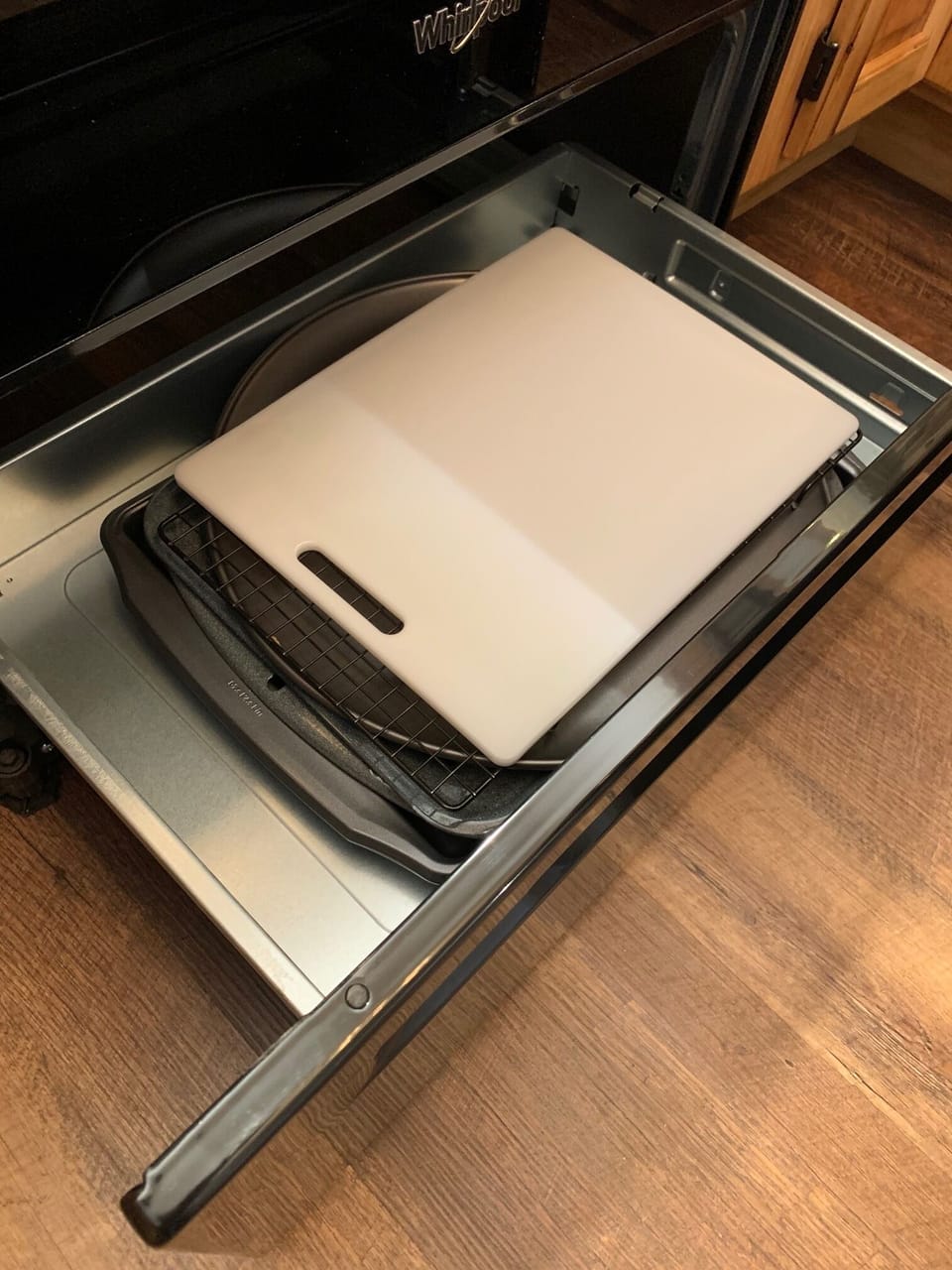 Oven drawer contains cutting board, cookie sheets, pizza sheet, and cooling rack