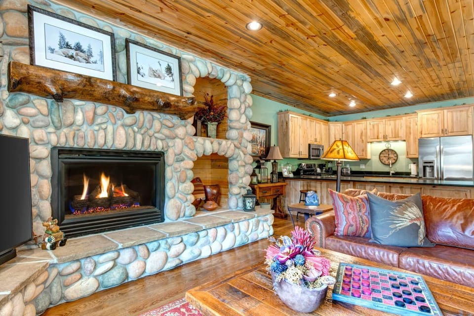 Gather in the living room with vaulted ceilings, a stone fireplace, and a Smart TV, perfect for relaxing after a day outdoors.