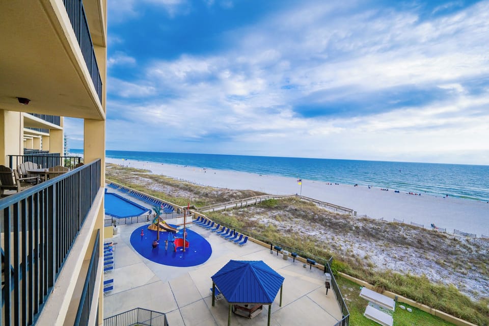Enjoy a serene view of the beach from the balcony, overlooking the vibrant pool area with a pirate splash playground
