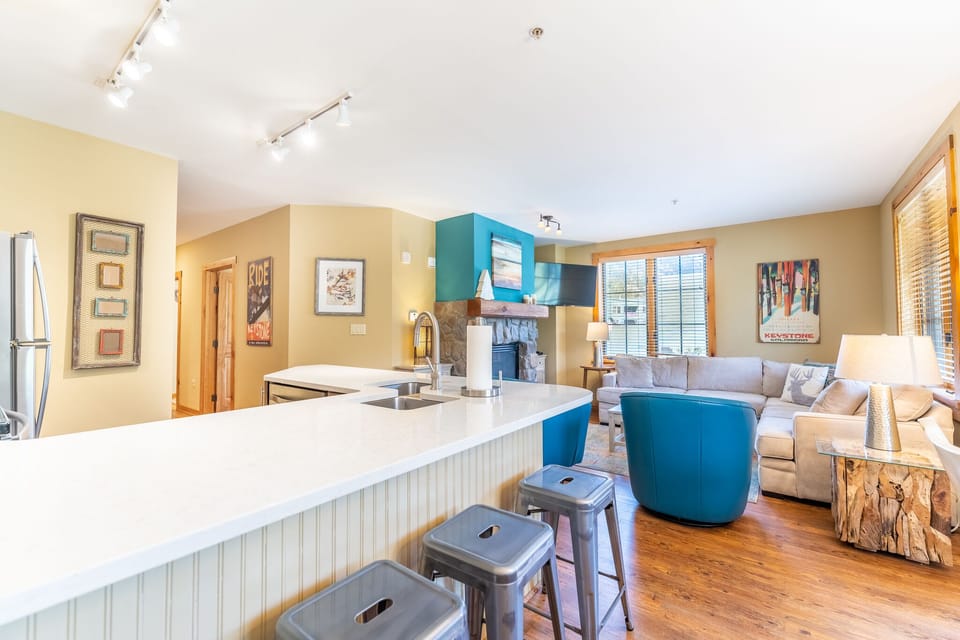 You'll love this open-concept space where vibrant blue accents and warm wood tones create the perfect atmosphere for cooking and relaxing together.