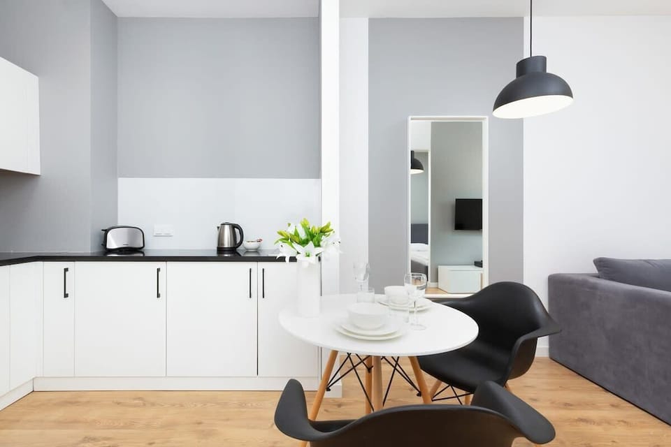 A compact and modern kitchenette with white cabinets and black accents. It includes a sink, stove, and ample counter space.