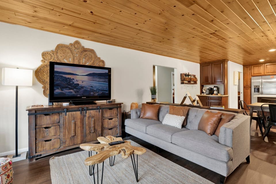Cozy mountain living room with a stone fireplace, comfy seating, and smart TV—perfect for relaxing evenings, movie nights, and warm cabin vibes after outdoor adventures.