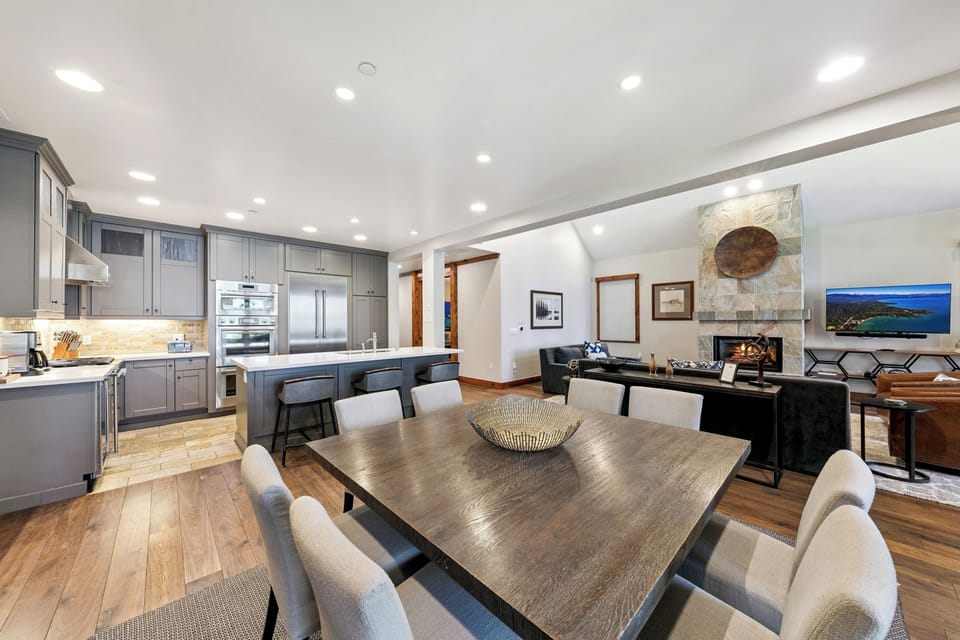 Your modern mountain retreat features a stunning open-concept layout with chef's kitchen, elegant dining space, and cozy living area with stone fireplace.