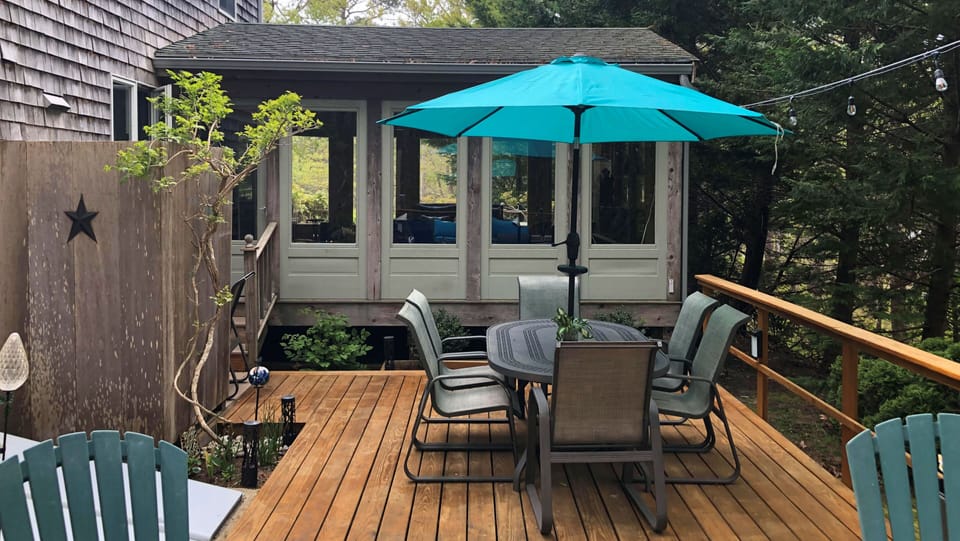 Large back deck with dining table, lounge furniture, gas grill and outdoor shower