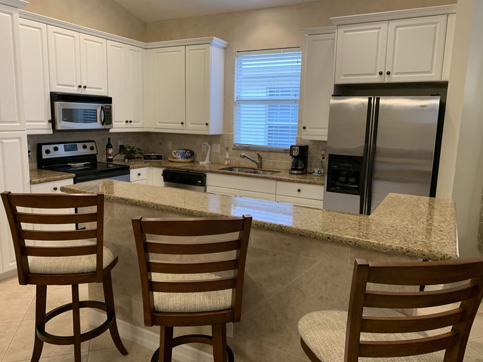 Well equipped kitchen with stainless appliances and three swivel bar stools