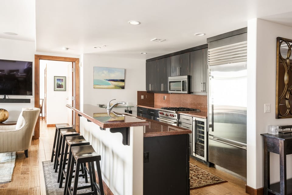 Dual tiered red granite kitchen island with wooden bar stools for 4