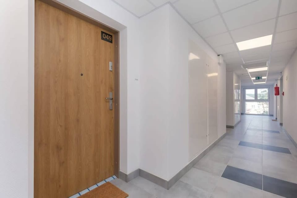 A clean and well-lit hallway with wooden doors, modern flooring, and recessed lighting.