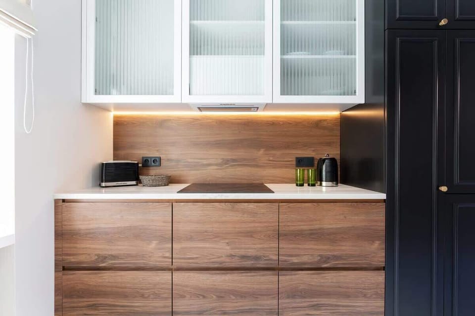 A sleek, modern kitchen with dark cabinets and wooden countertops. The space is clean and stylish.
