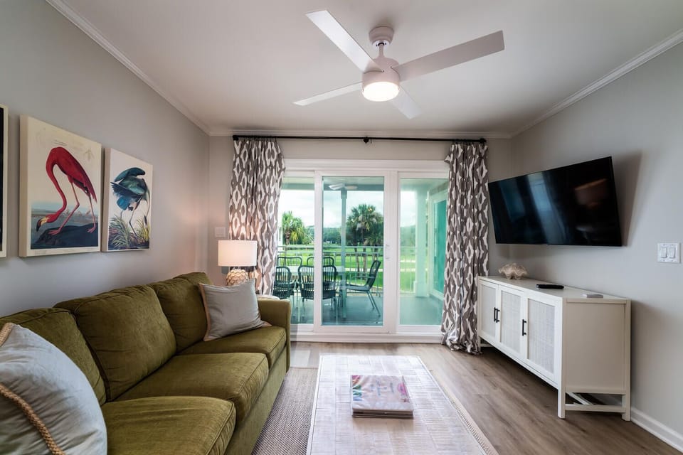 The living area has a ceiling fan and large Smart TV