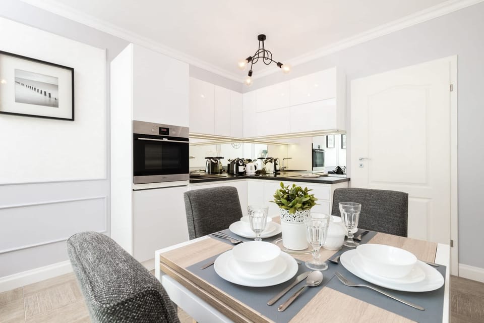 A dining area with a round table set for two, located next to the open-plan kitchen. The space has modern decor and warm lighting.
