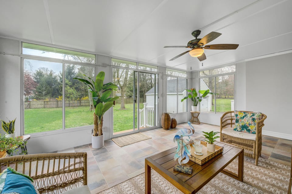 Sunroom is filled with decorative pillows, plants, and art.