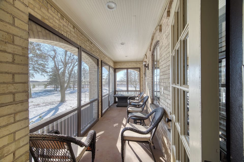 Screened in porch with fire table and view of open yard and orchard