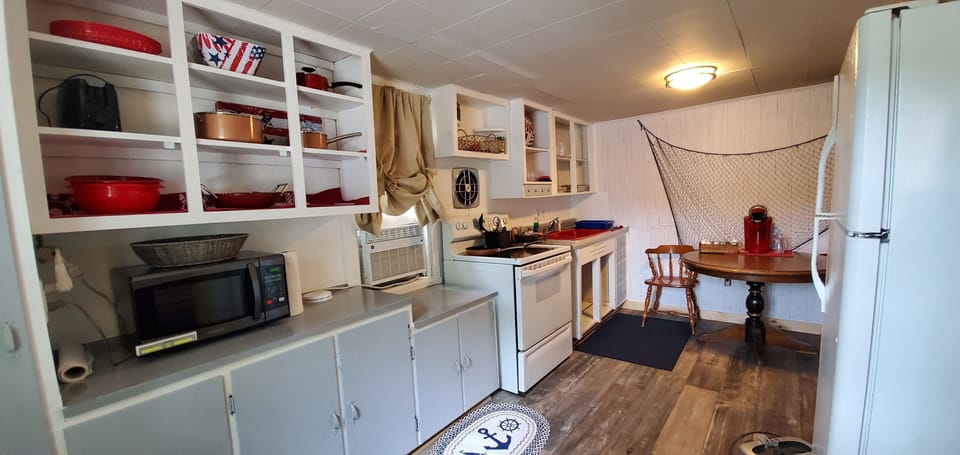 Kitchen has full sized refrigerator, stove, and microwave. 