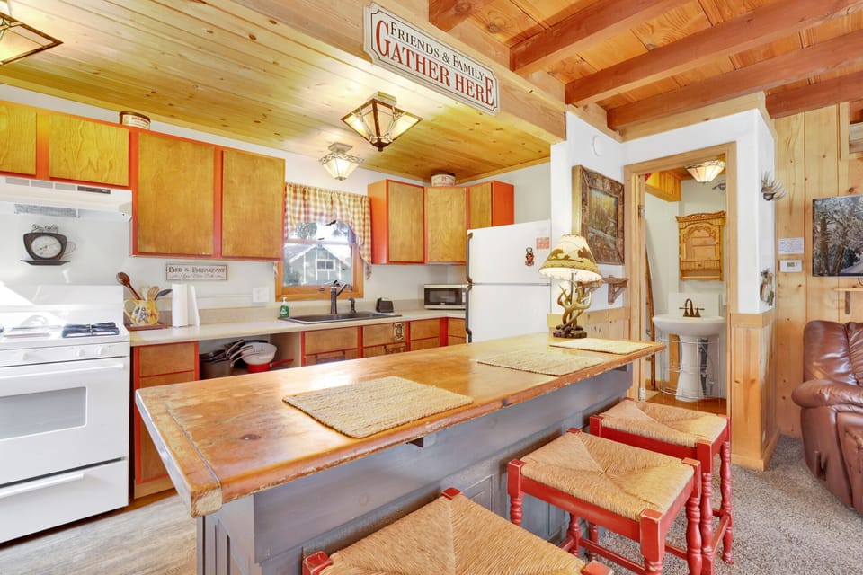 Fully equipped cabin kitchen with cabinets, stove, fridge, coffee maker, and dining table—perfect for home-cooked meals, morning coffee, and a cozy, comfortable stay.
