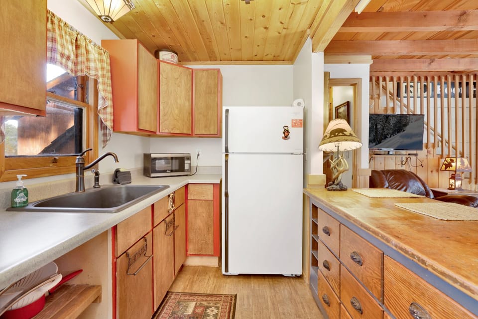 Fully equipped cabin kitchen with cabinets, stove, fridge, coffee maker, and dining table—perfect for home-cooked meals, morning coffee, and a cozy, comfortable stay.