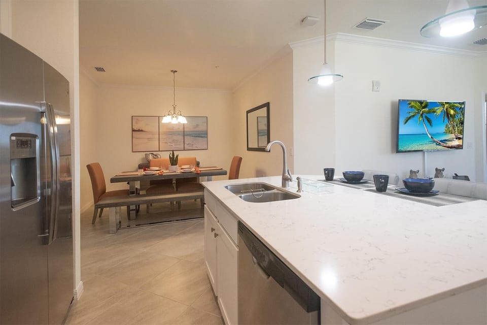 Stainless steel refrigerator stands beside tiled floors and a dining nook with leather chairs and a bench.