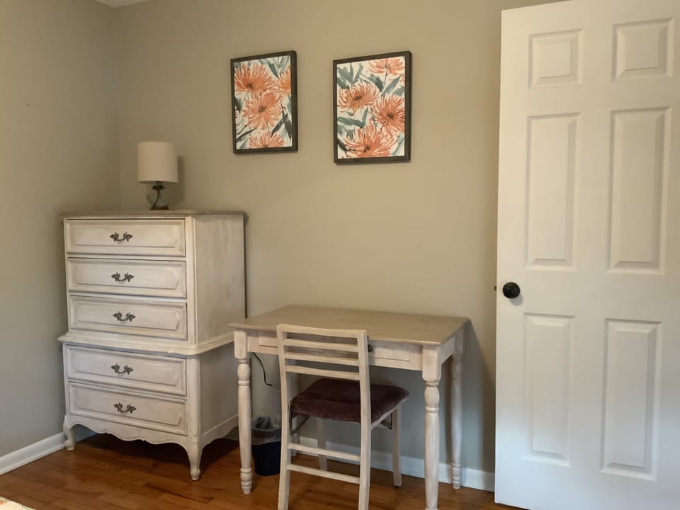 Desk and dresser is room with queen bed