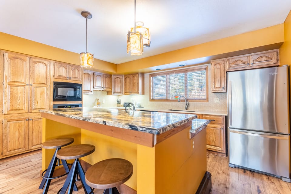 Your fully equipped kitchen features granite countertops, stainless steel appliances, and a breakfast bar perfect for morning coffee or casual meals.
