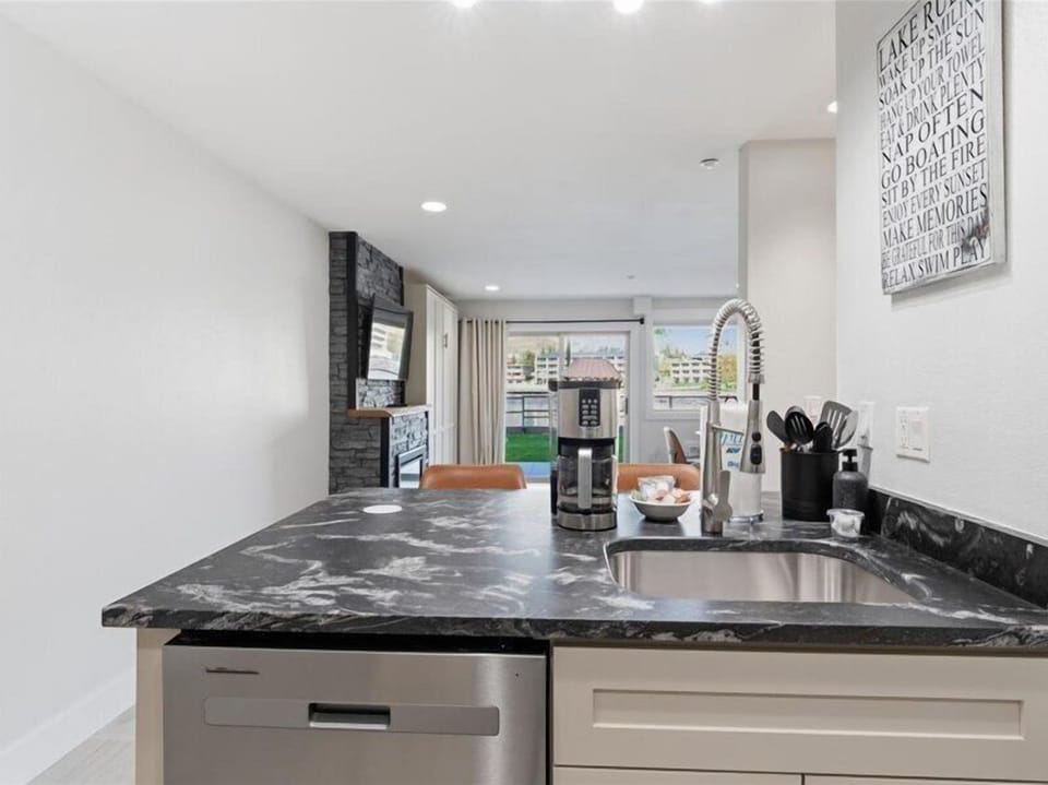 Your sleek kitchen features stunning dark granite countertops and modern appliances, flowing seamlessly to the dining area and private balcony beyond.