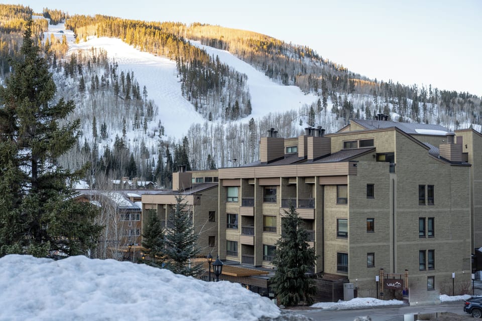 A slopeside property location beneath snow-covered ski runs, with the groomed trails and winter forest creating the perfect alpine setting for your mountain getaway.