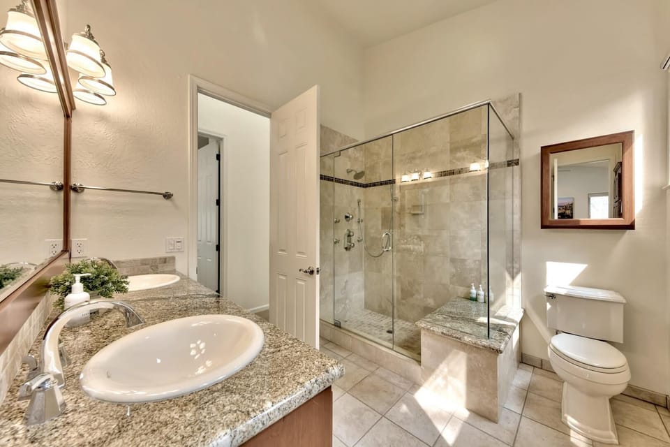 Indulge in your private spa-like bathroom featuring elegant granite countertops, a spacious glass-enclosed shower, and luxurious finishes throughout.