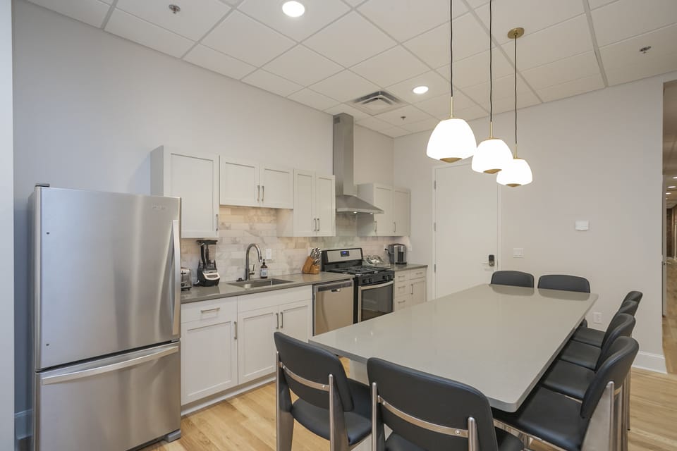 - Modern kitchen with stainless appliances and sleek white cabinetry   - Spacious island seating is perfect for meals and gathering   - Bright lighting and clean design enhance the cooking experience