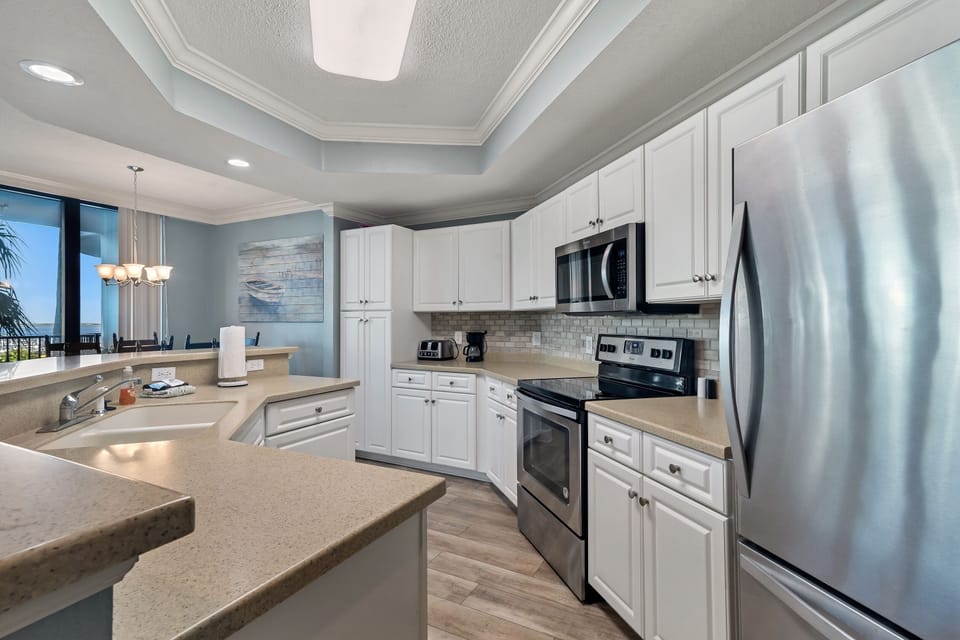 Culinary delights meet captivating views in this well-appointed kitchen, featuring ample counter space and a breakfast bar, all while offering an open sightline to the comfortable living room and beyond.