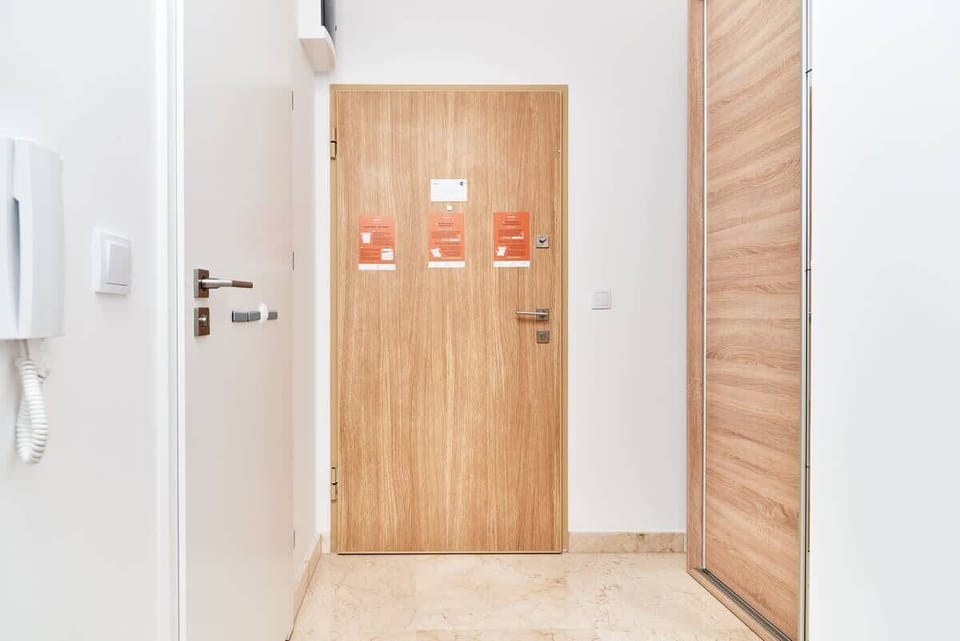 A minimal hallway with white walls and wooden doors, connecting the rooms in the apartment.