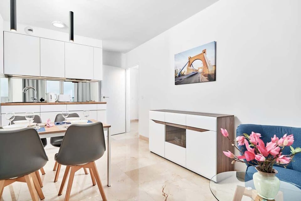 A compact kitchen with modern cabinets, a dining table set for four, and bright lighting.

