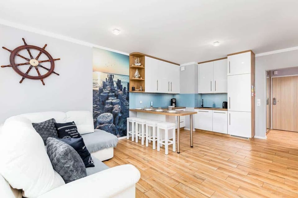 A well-lit living room with a white corner sofa, navy cushions, and a nautical-themed decor.