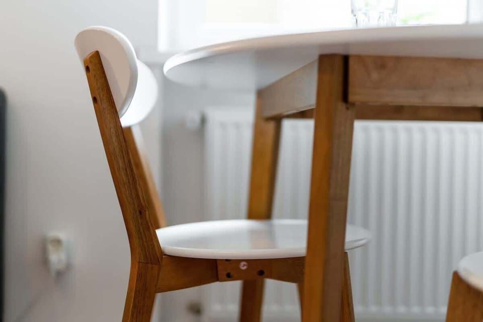 A close-up of a light wood chair near a dining table, matching the minimalist interior.