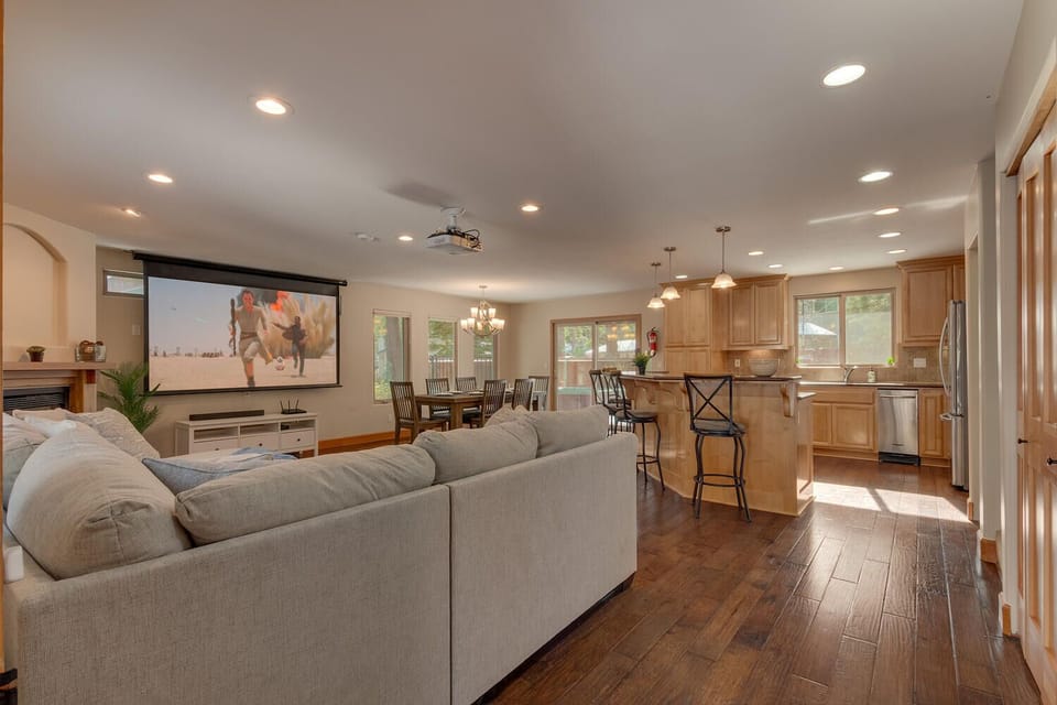 - Large open living area with kitchen connection  
- Projector screen and rustic wood flooring warmth  
- Ideal for gatherings, cooking, and movie nights
