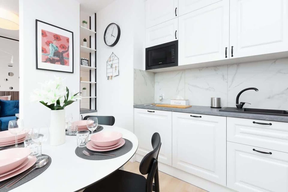 A dining area with a round table, decorated with simple yet elegant tableware, located next to a large window.