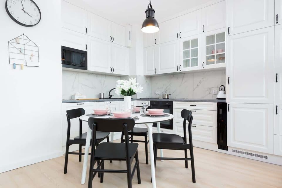 A sleek kitchen with white cabinets, black countertops, and modern appliances, designed with minimalistic elegance.