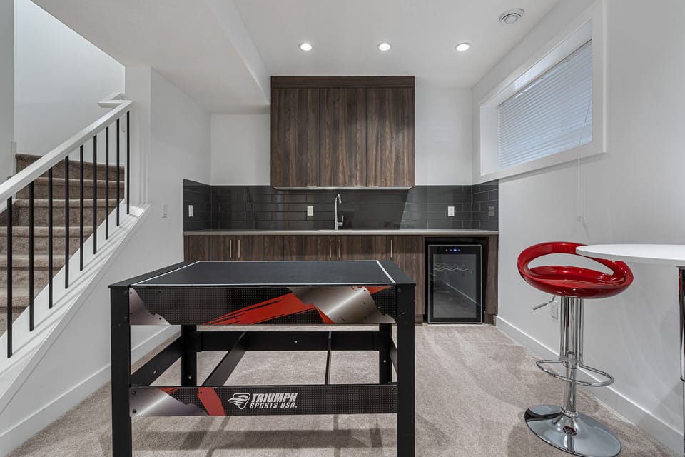 clean bright and spacious game room in basement with fridge