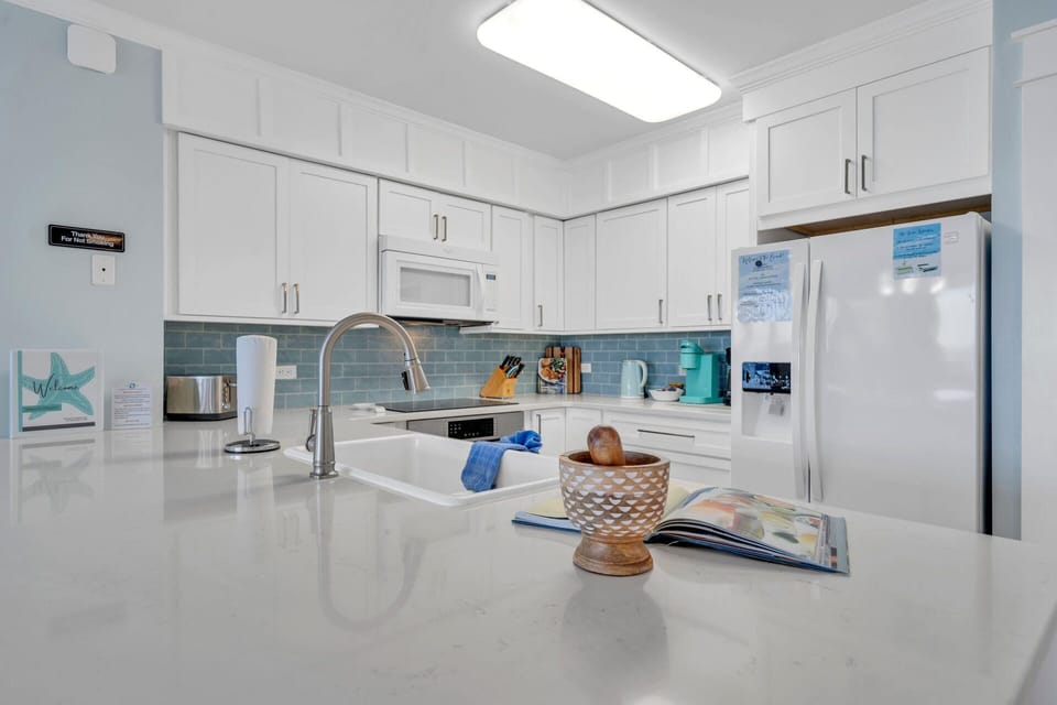 Your bright, fully-equipped kitchen invites you to create memorable meals with gleaming countertops, modern appliances, and coastal charm.