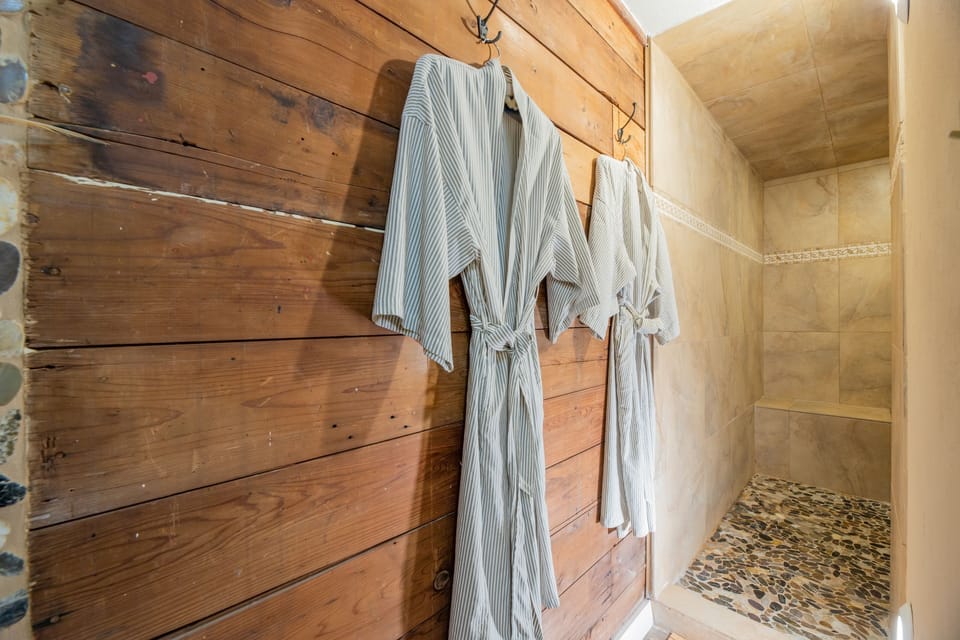 Shiplap and robes leading to river rock walk in shower in downstairs suite
