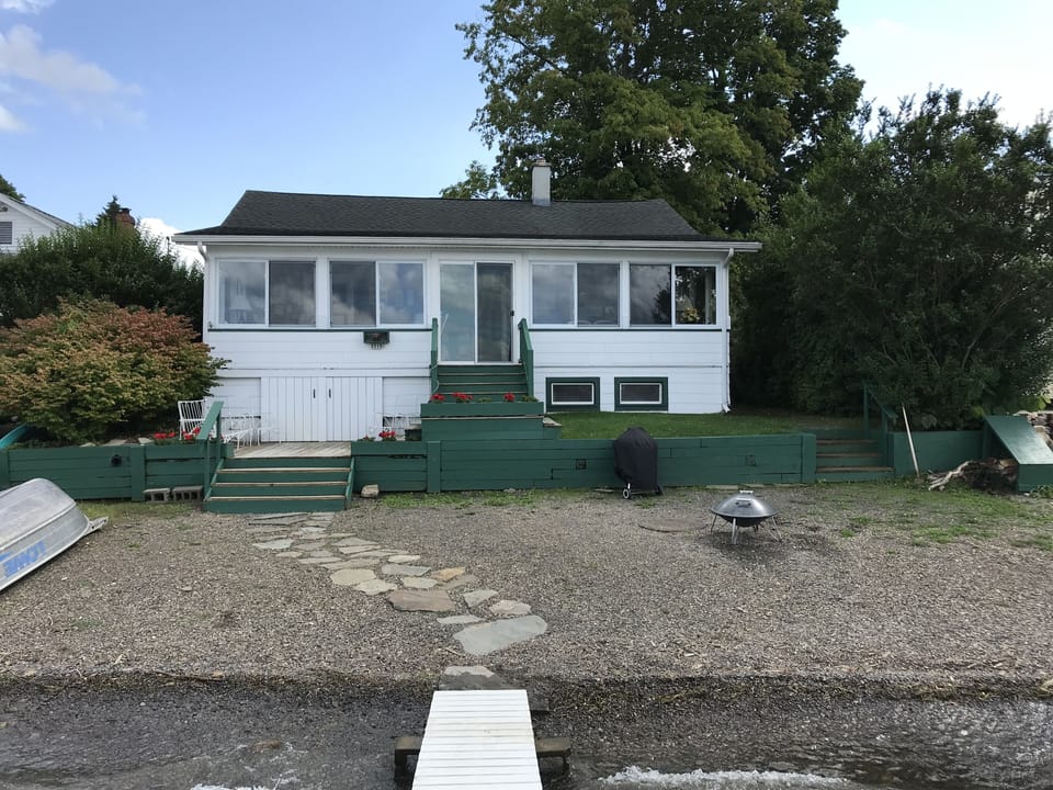 Lakeside of cottage viewed from the dock. Fire pit and Weber grill on the beach.