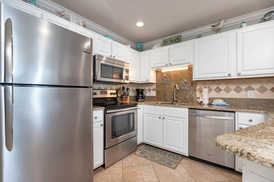 Cook and gather in the bright kitchen featuring stainless appliances and coastal decor for a delightful experience