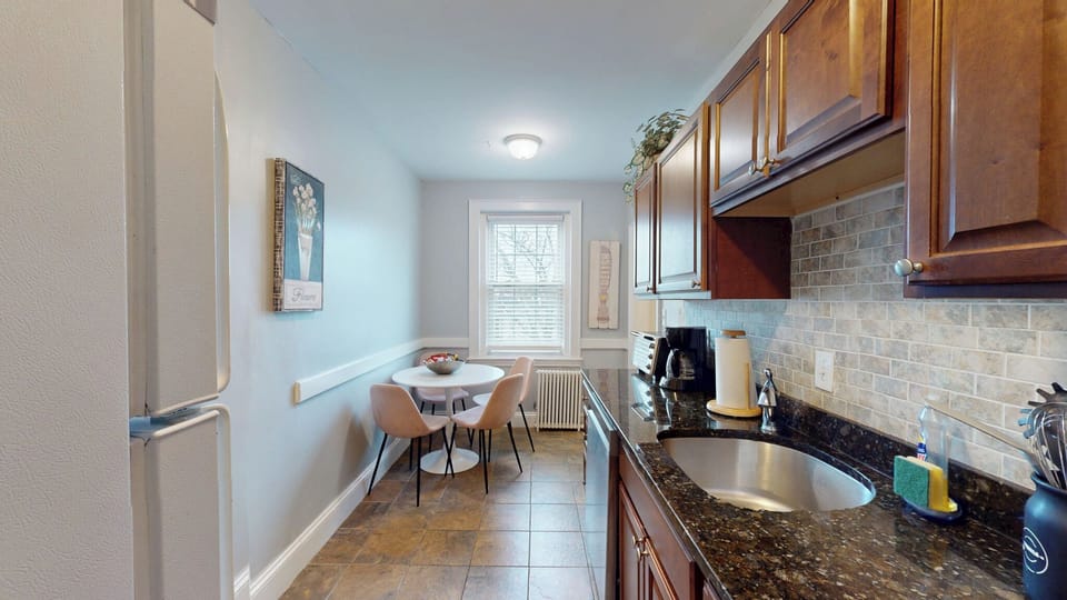 Sunlit kitchen with 3 seater dining table, coffee maker, etc