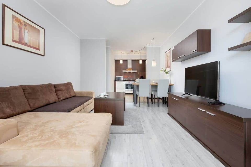 Elegant and cosy living room with sofa, dining area, coffee table, and kitchenette.